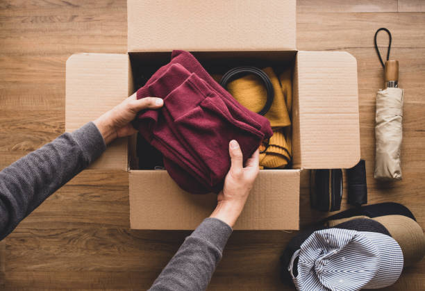 Người đang sắp xếp quần áo và vật dụng cá nhân vào thùng carton để gửi đồ cá nhân sang Đức, thể hiện sự kết nối giữa gia đình Việt Nam và người thân ở châu Âu.