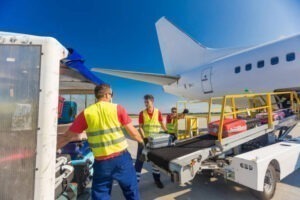 Nhân viên sân bay đang bốc xếp hành lý lên máy bay, minh họa cho dịch vụ gửi hàng xách tay đi Đức nhanh và an toàn.