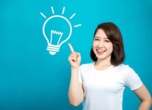Người phụ nữ mỉm cười chỉ vào biểu tượng bóng đèn tượng trưng cho ý tưởng tiết kiệm chi phí – minh họa cho bài viết gửi hàng đi Đức giá rẻ.