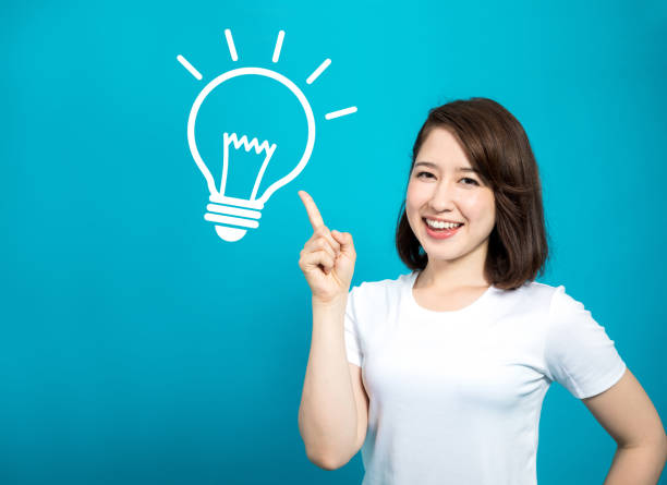 Người phụ nữ mỉm cười chỉ vào biểu tượng bóng đèn tượng trưng cho ý tưởng tiết kiệm chi phí – minh họa cho bài viết gửi hàng đi Đức giá rẻ.