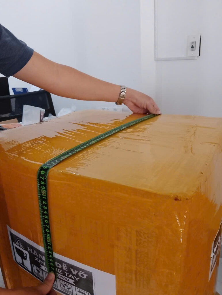 Nhân viên Xanh THL Logistics đo kích thước thùng hàng để tính trọng lượng quy đổi, minh họa kinh nghiệm gửi hàng đi Đức chính xác và tiết kiệm chi phí.